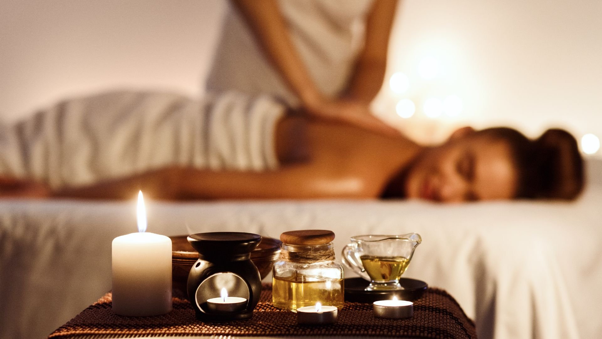 Relaxing spa setting with massage oils, candles, and person receiving treatment