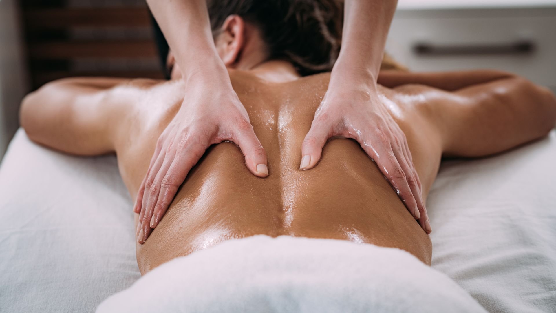 Professional massage therapy with hands working on oiled back
